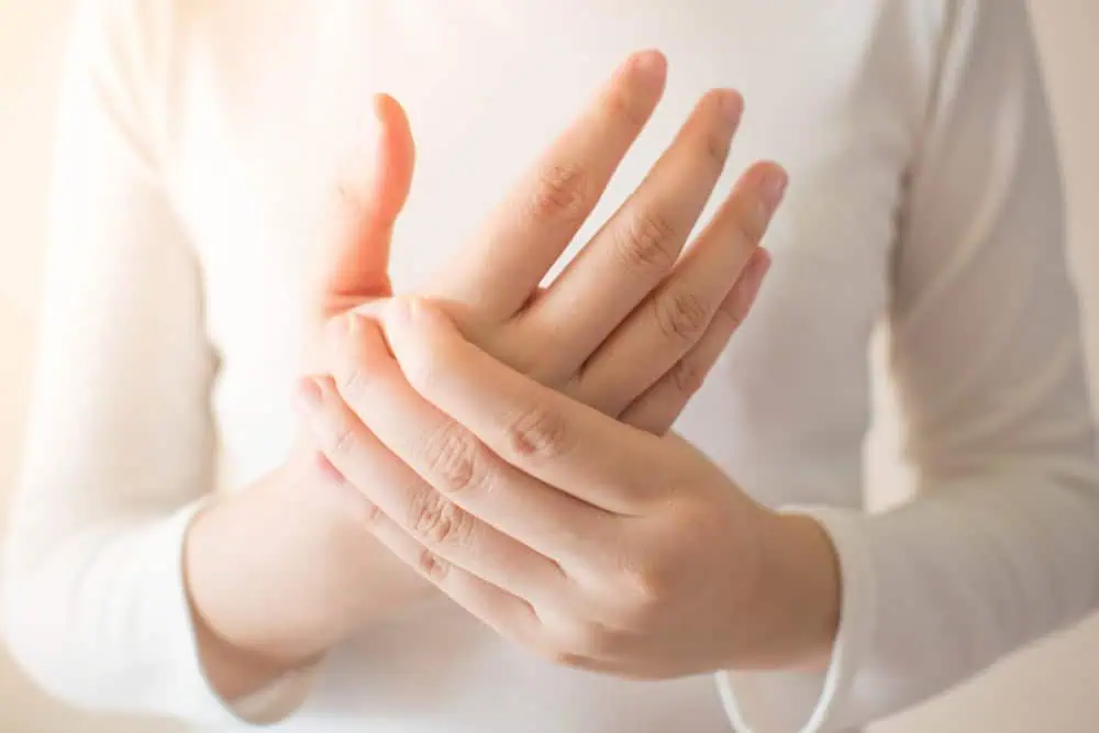 Young Female In White T-shirt Suffering From Pain In Hands