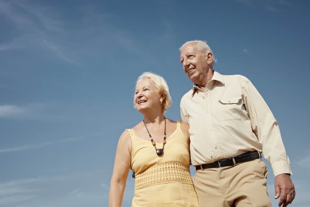 Senior Caucasian Couple Walking On Sunny Day And Hugging